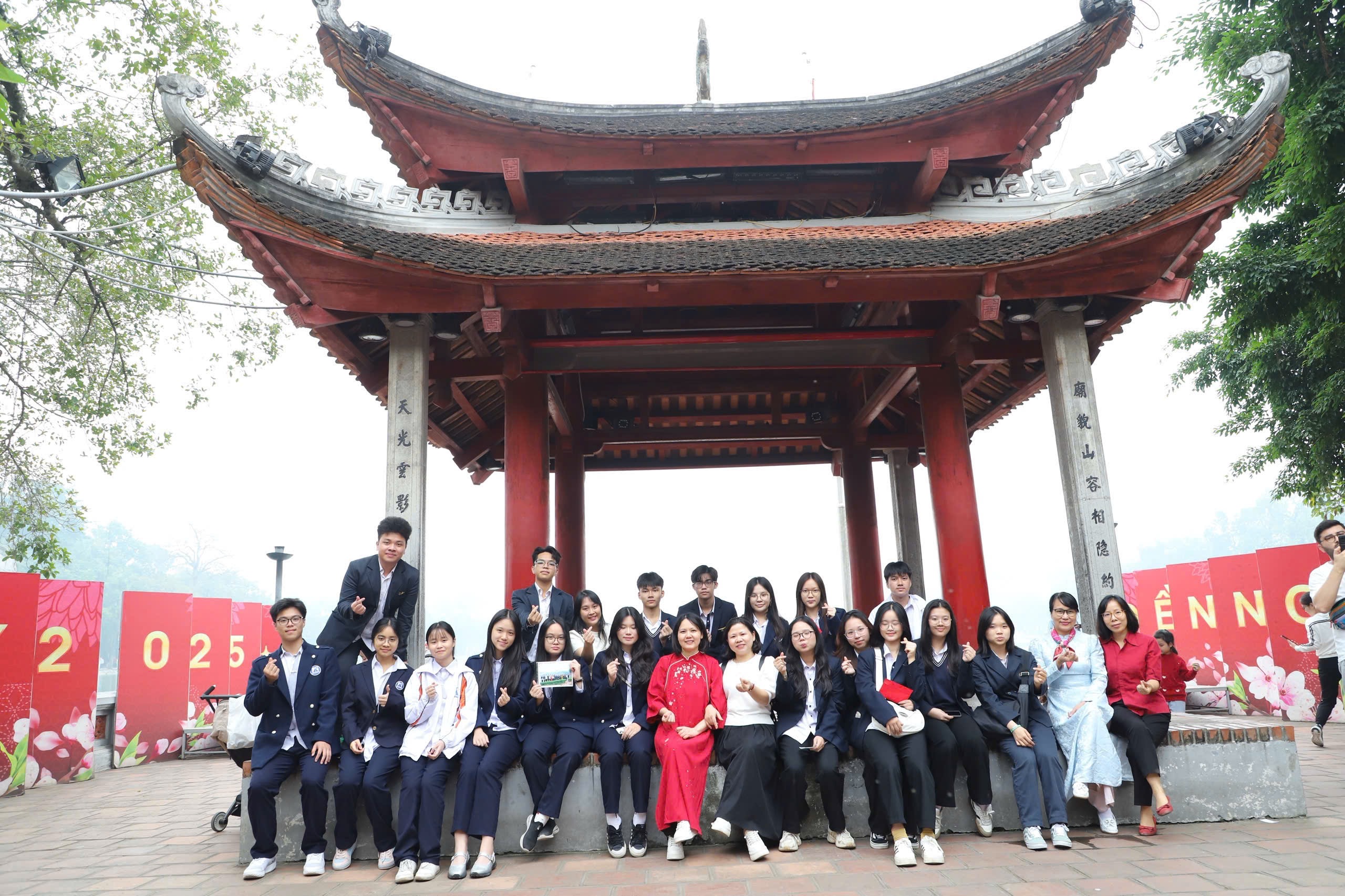 Students gathered on the steps of a red pavilion by the lake