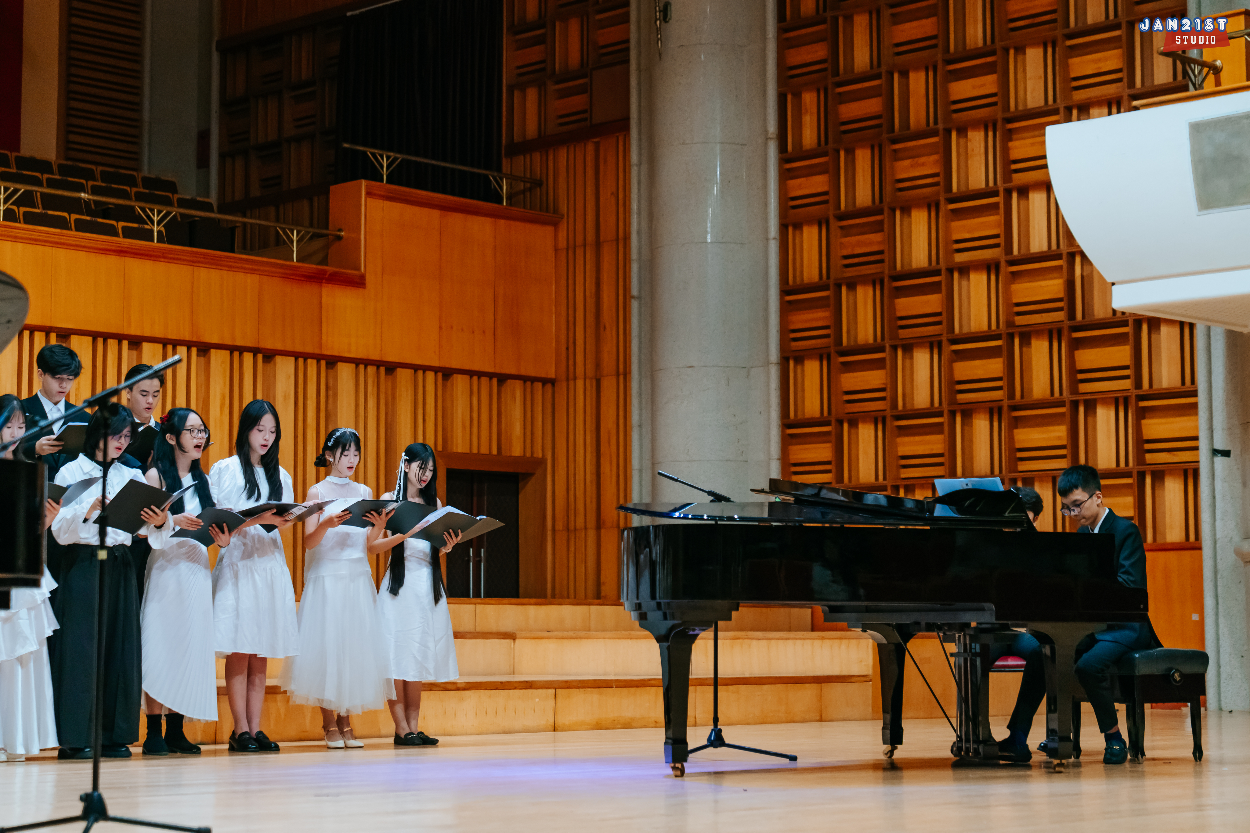 Singers beside a grand piano in a concert hall
