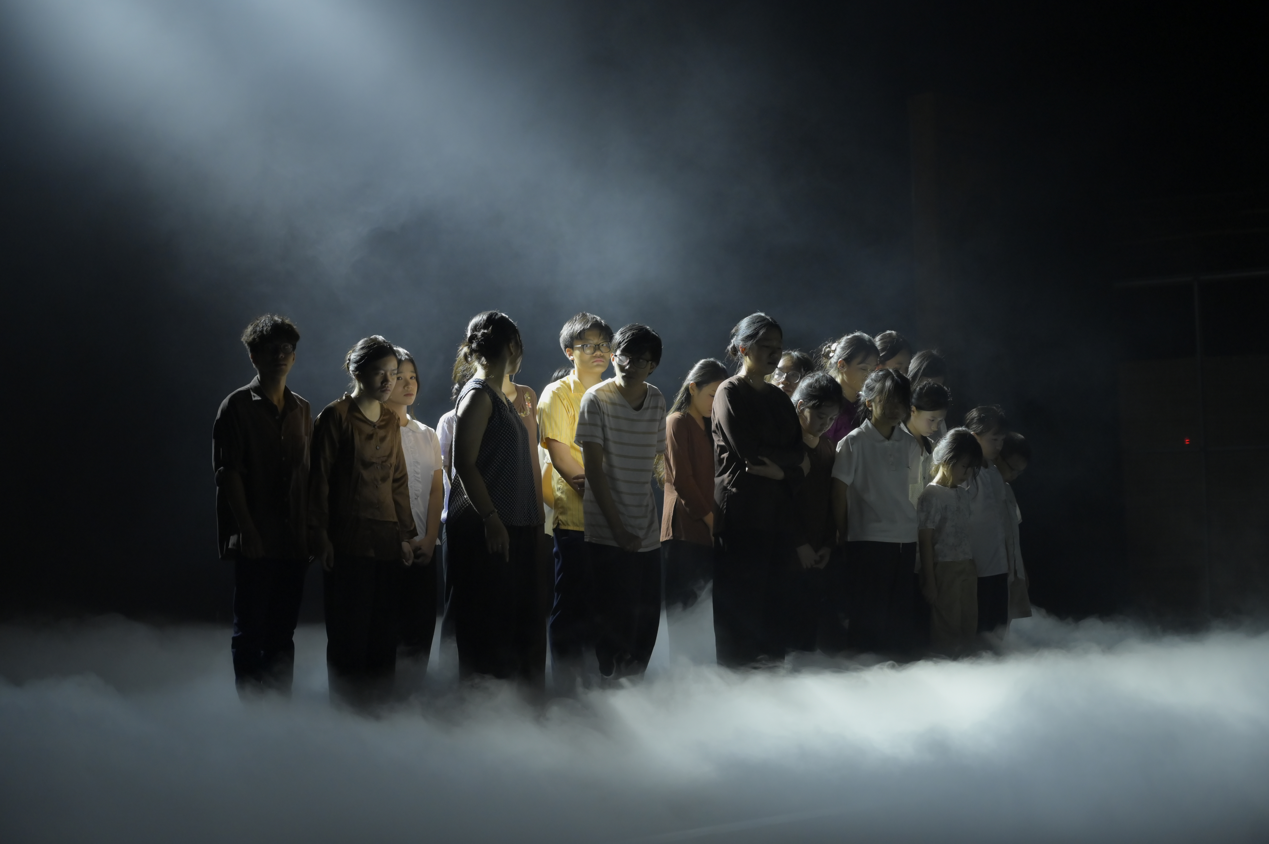 Actors standing in stage fog under a single beam of light