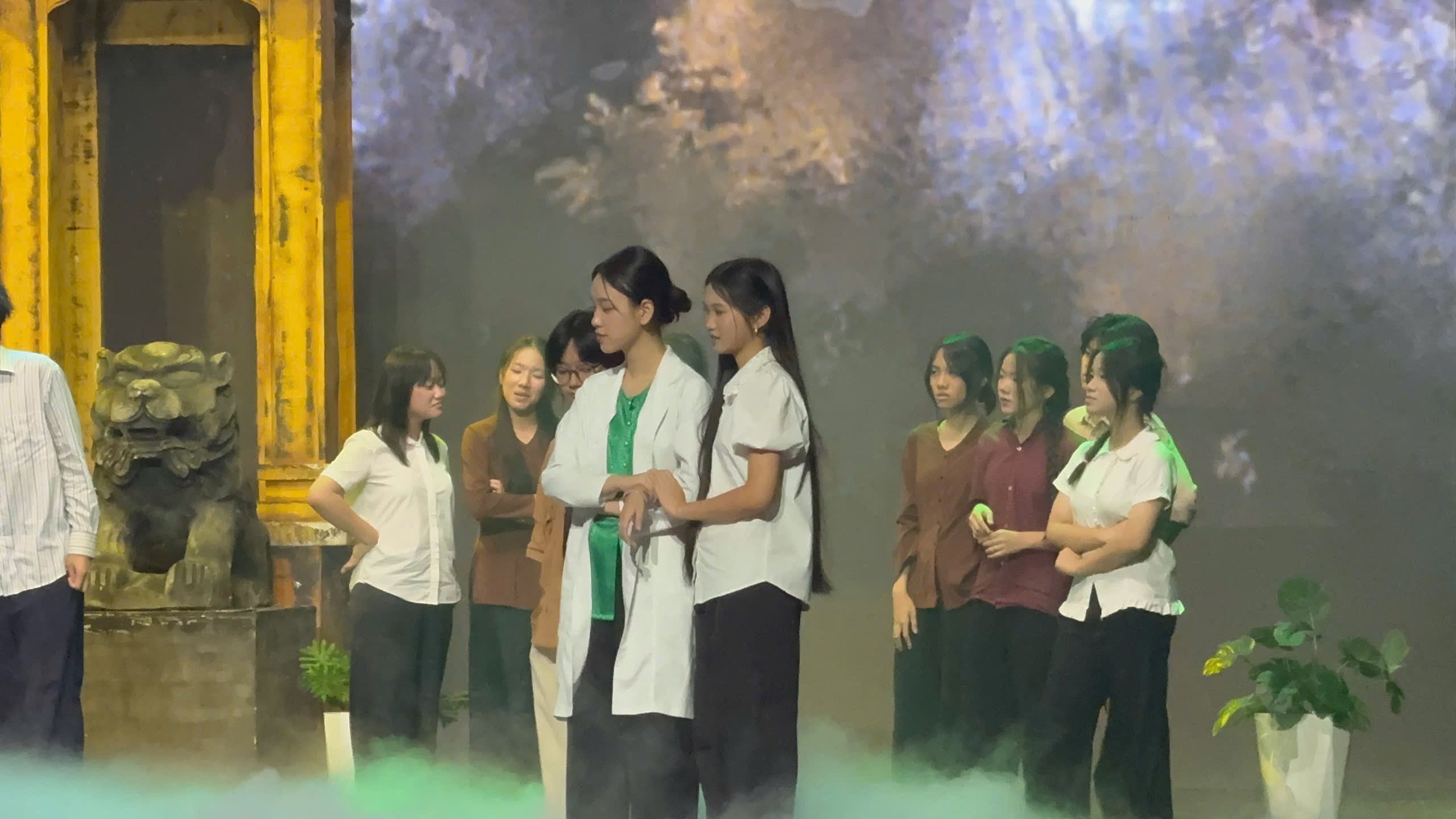 Gia Han in costume with the cast in front of a painted village backdrop
