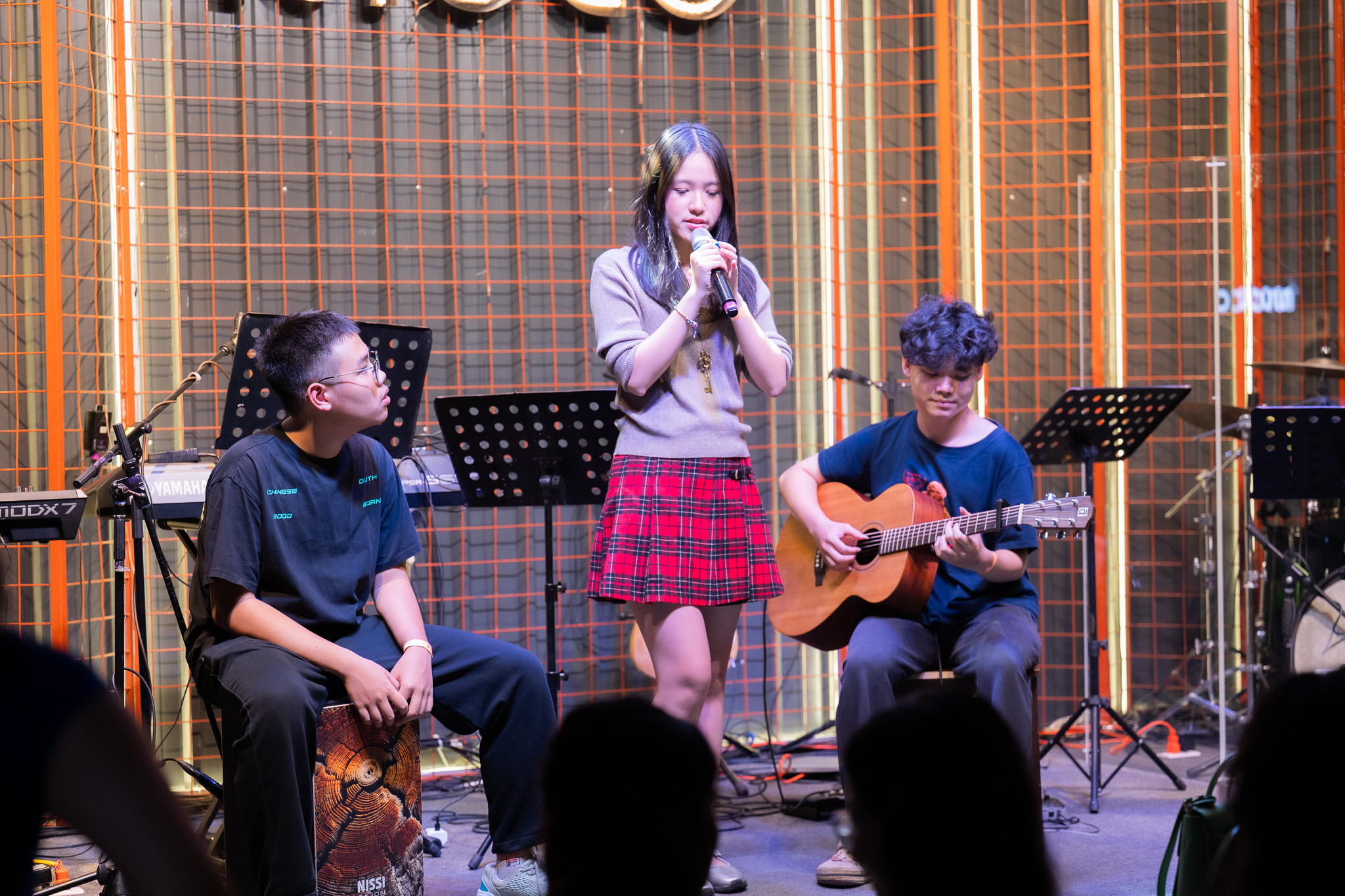 An acoustic set: Gia Han singing between a cajon player and a guitarist