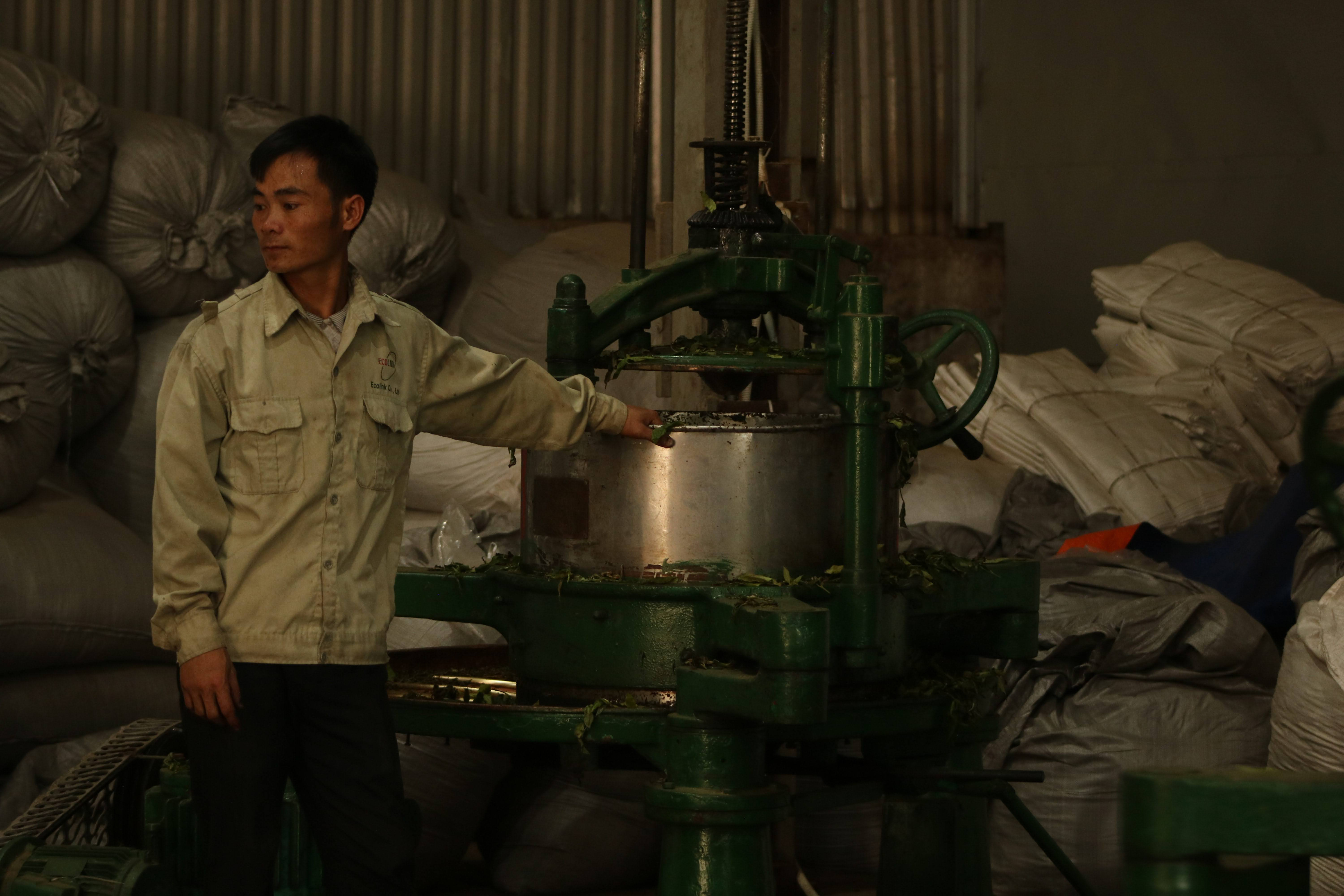 A tea maker at work beside his roasting drum